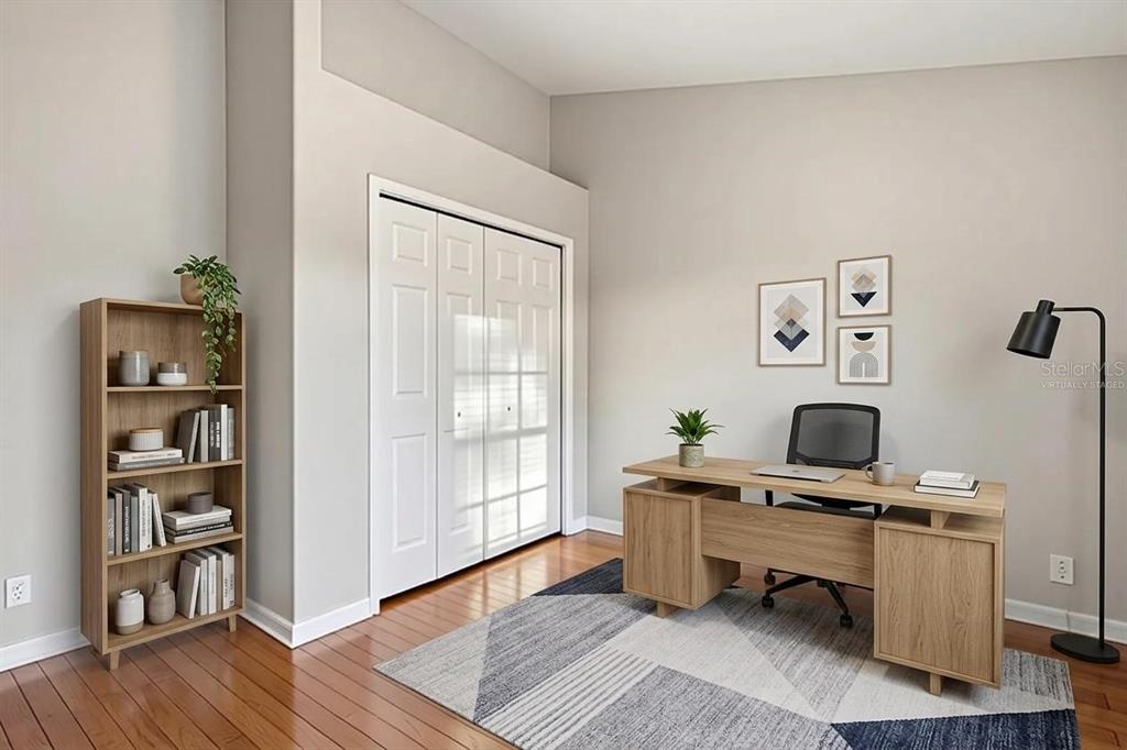 A home office features a wooden desk, a bookshelf, a rug, and white closet doors — 13157 THOROUGHBRED LOOP, LARGO, FL