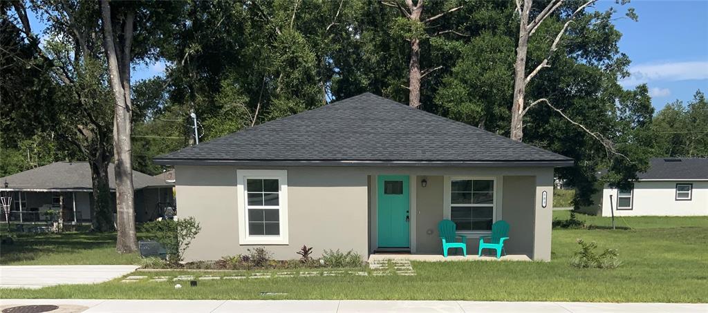 A gray single-story house with a teal front door and two teal chairs on the porch — 503 NW 60 AVENUE, OCALA, FL