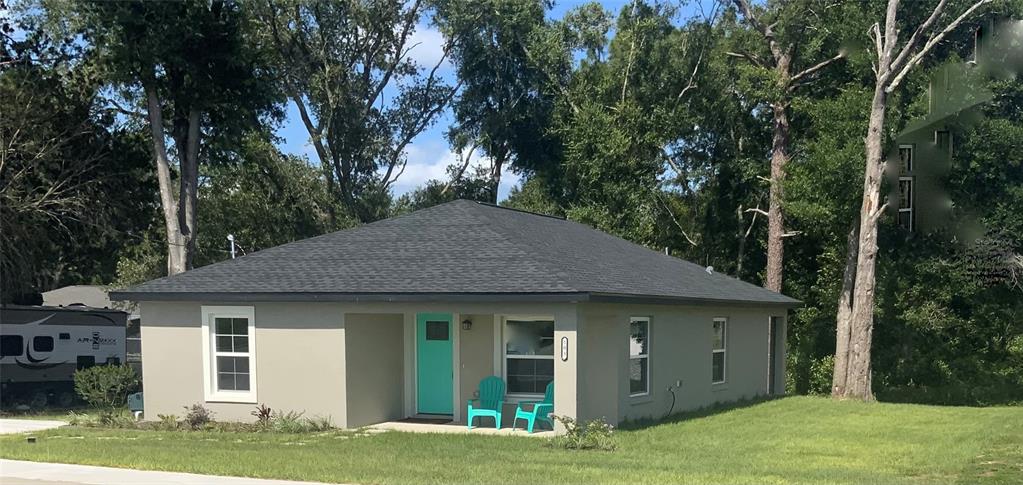 A single-story house with a gray exterior, a teal front door, and a dark shingled roof — 503 NW 60 AVENUE, OCALA, FL