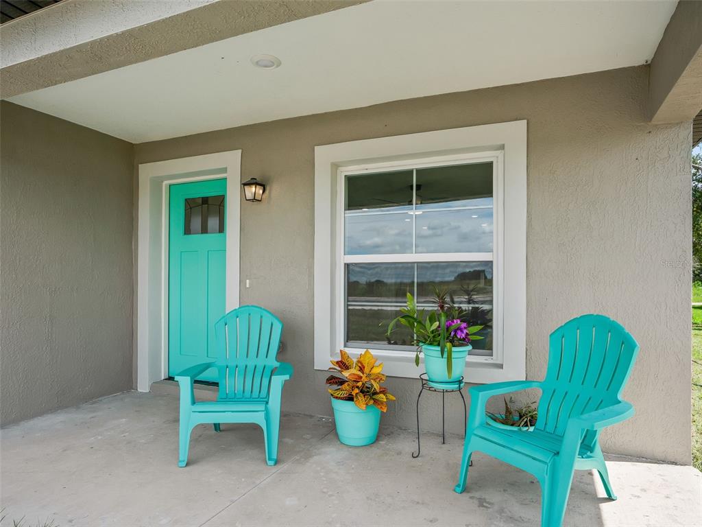 A covered porch features two turquoise Adirondack chairs, two potted plants, and a turquoise front door — 503 NW 60 AVENUE, OCALA, FL