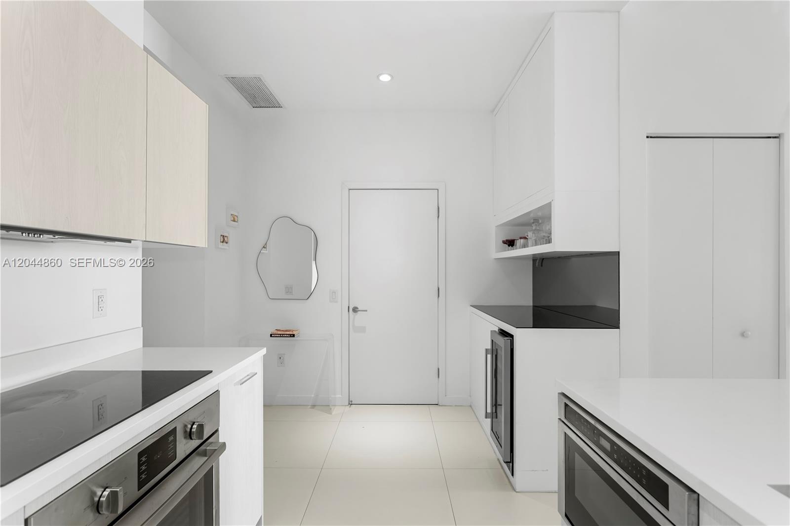A modern kitchen features white cabinetry, stainless steel appliances, and a black countertop — 501 NE 31st St # 204, Miami FL 33137, MIAMI, FL