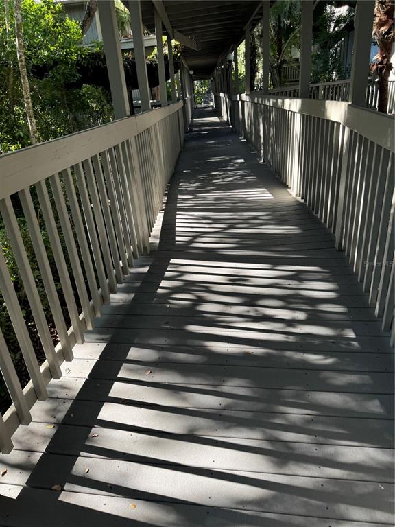 A covered wooden walkway with railings leads through a shaded outdoor area — 1323 LANDINGS DRIVE UNIT 12, SARASOTA, FL