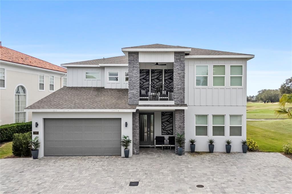 A two-story house with a stone-accented facade, a gray garage, and a paved driveway — 7442 GATHERING COURT, KISSIMMEE, FL