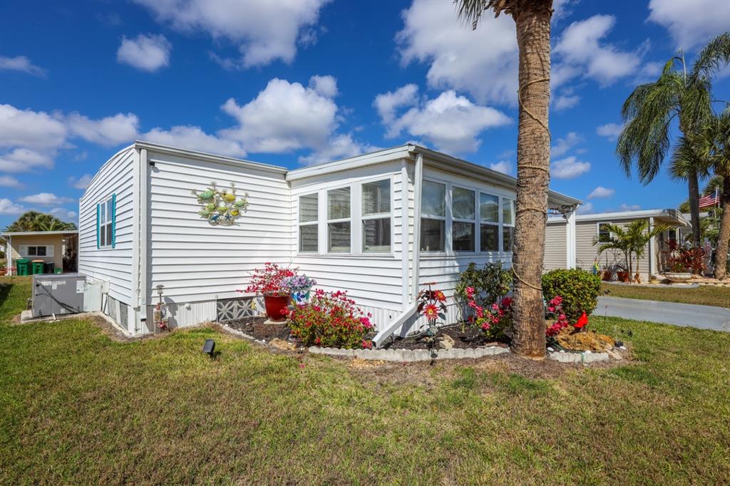 A single-story mobile home with a white exterior, a carport, and a palm tree — 2100 KINGS HIGHWAY UNIT 406, PORT CHARLOTTE, FL