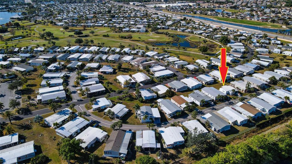 An aerial view shows a manufactured home community with a red arrow pointing to a house — 2100 KINGS HIGHWAY UNIT 406, PORT CHARLOTTE, FL