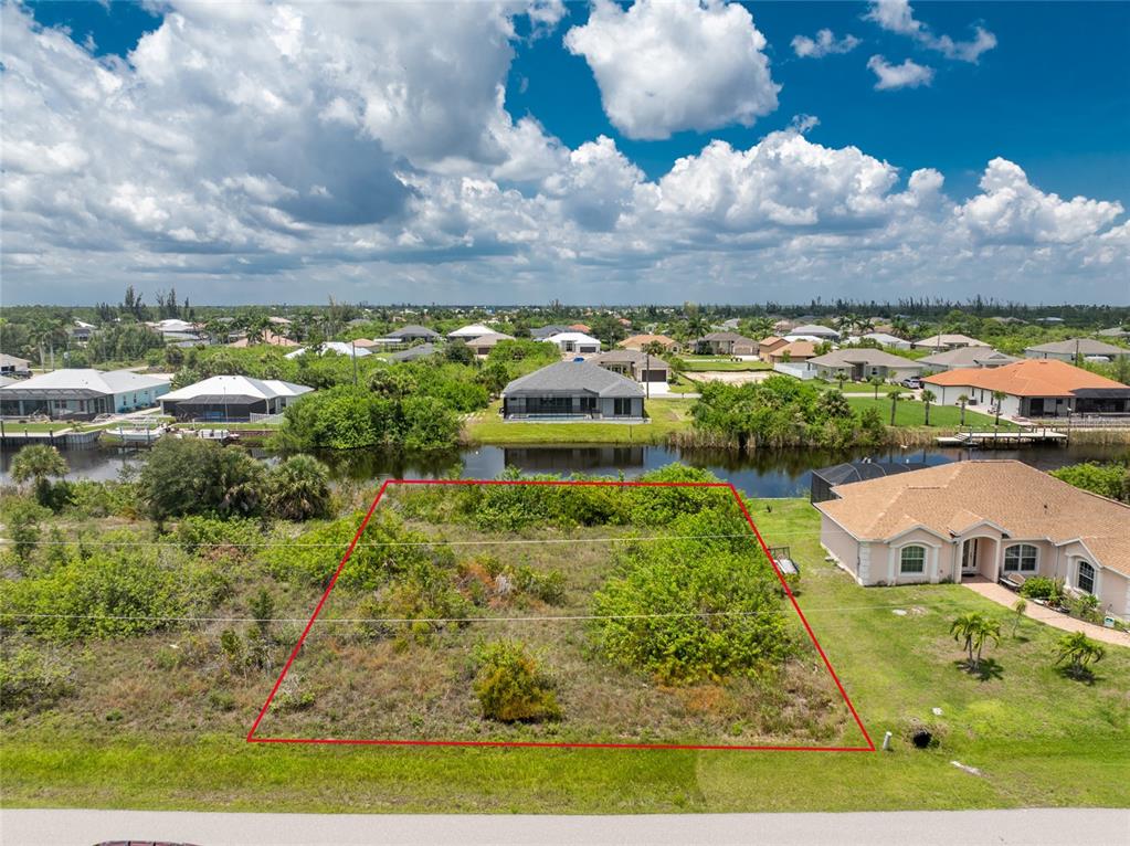 An aerial view shows a vacant, rectangular lot outlined in red bordering a canal — 15610 APPLEWHITE CIRCLE, PORT CHARLOTTE, FL