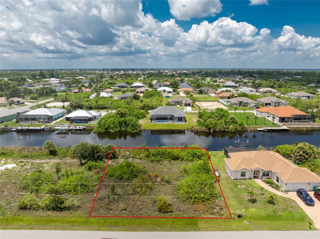An aerial view shows a vacant, rectangular lot outlined in red next to a house — 15610 APPLEWHITE CIRCLE, PORT CHARLOTTE, FL