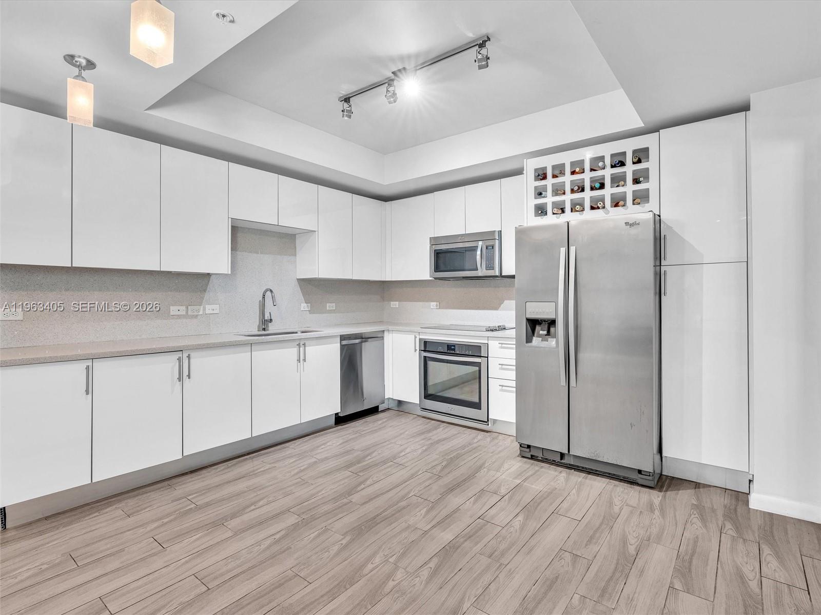 A modern kitchen features white flat-panel cabinets, stainless steel appliances, and light wood-look flooring — 999 SW 1st Ave # 1201, Miami FL 33130, MIAMI, FL