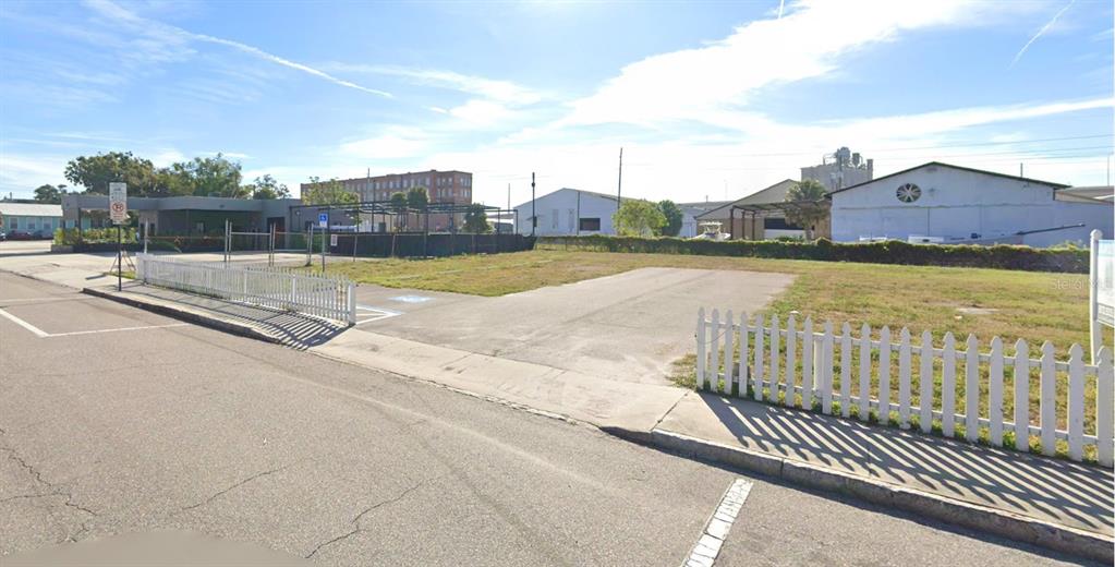 A vacant, fenced-in paved lot sits adjacent to a building under a blue sky — 1715 E 4TH AVENUE, TAMPA, FL