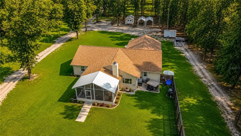 An aerial view shows a house with a screened porch, hot tub, and detached outbuildings — 15970 NW 53RD STREET, MORRISTON, FL
