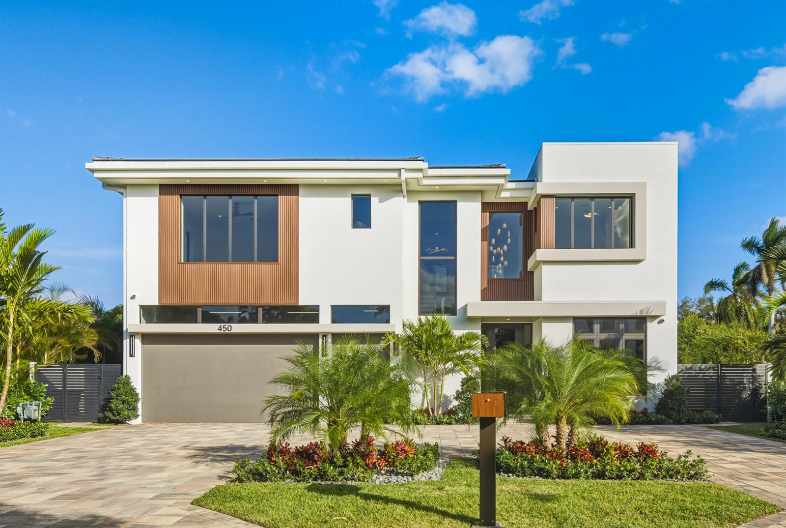 A modern two-story house features a flat roof, wood-slat accents, and a paved driveway — 450 NE Spanish Court, Boca Raton FL 33432, BOCA RATON, FL