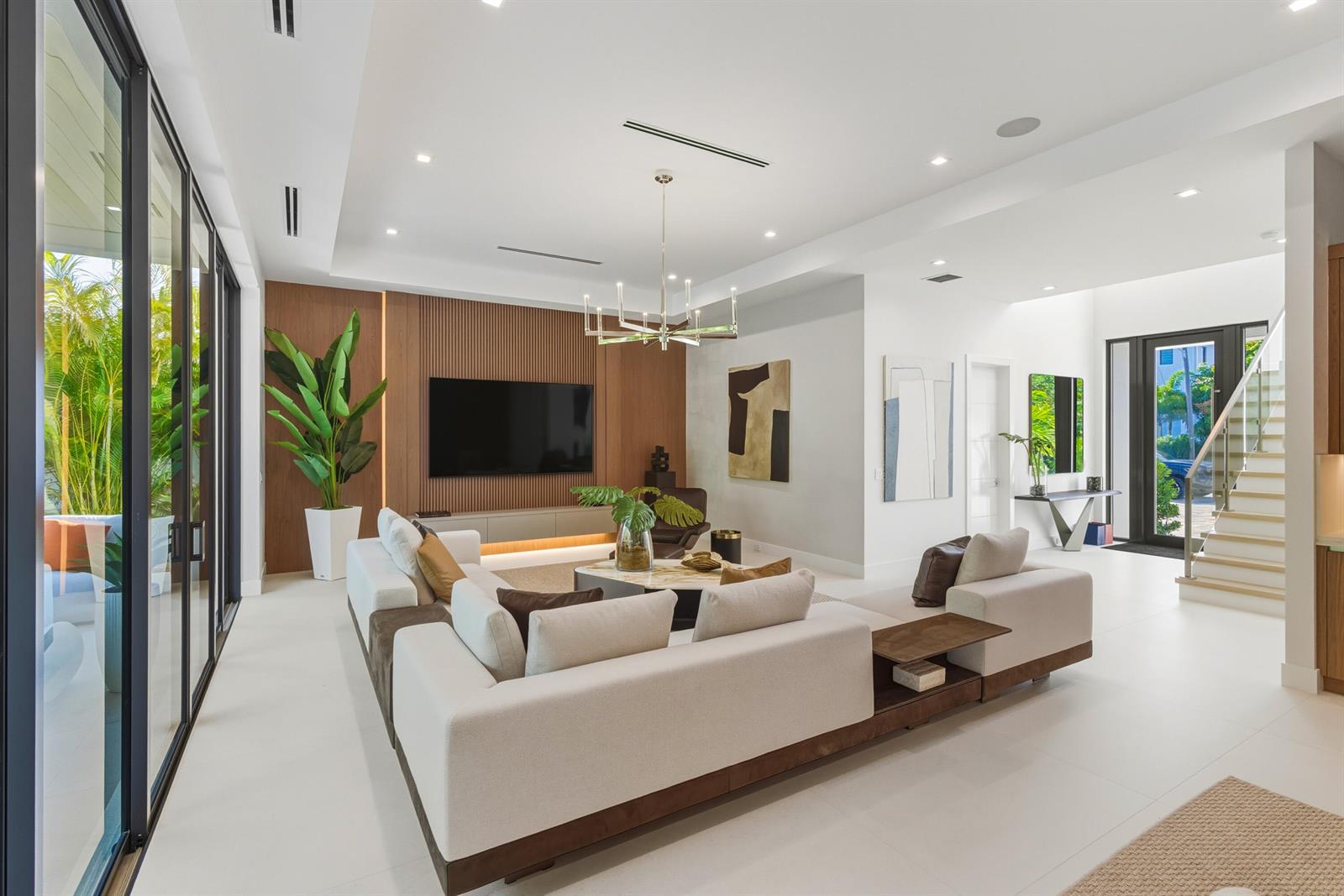 A modern living room features a slatted wood accent wall, sectional sofa, and glass doors — 450 NE Spanish Court, Boca Raton FL 33432, BOCA RATON, FL