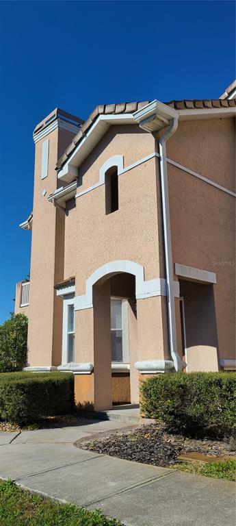 The exterior of a tan stucco building features a covered entryway and white trim — 17902 VILLA CREEK DRIVE UNIT 17902, TAMPA, FL