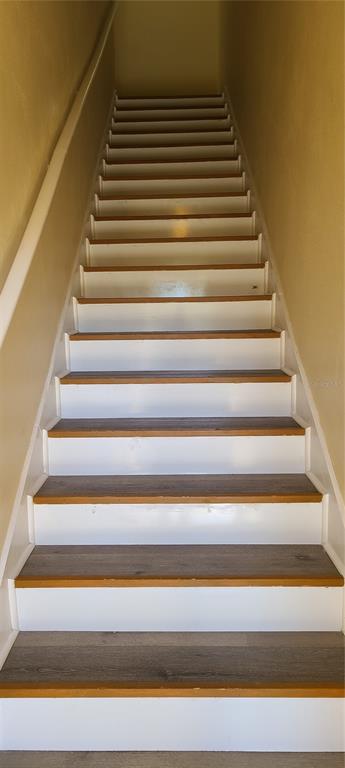 A straight staircase features white risers and wood-look treads between two plain beige walls — 17902 VILLA CREEK DRIVE UNIT 17902, TAMPA, FL