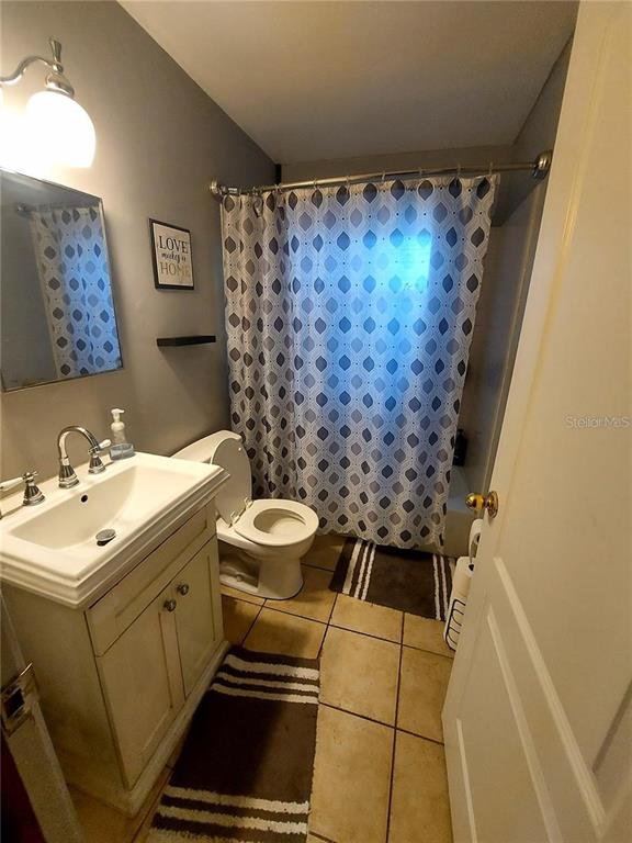 A bathroom features a white pedestal vanity, a toilet, and a shower with a patterned curtain — 448 N KANSAS AVENUE, DELAND, FL