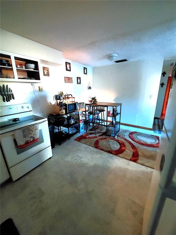 A kitchen features a white stove, a small dining table with stools, and a patterned rug — 448 N KANSAS AVENUE, DELAND, FL