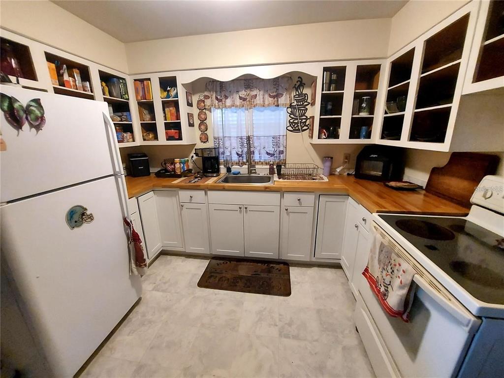 A kitchen features white cabinets, a wood countertop, a white refrigerator, and a white stove — 448 N KANSAS AVENUE, DELAND, FL
