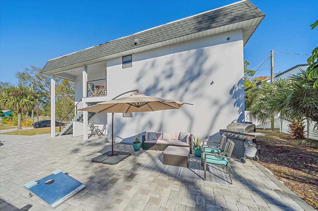 A paved patio features an outdoor seating area, a grill, and a large umbrella — 3710 IROQUOIS AVENUE, SARASOTA, FL