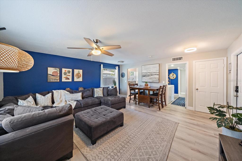 A living room features a blue accent wall, a large sectional sofa, and dining area — 3710 IROQUOIS AVENUE, SARASOTA, FL