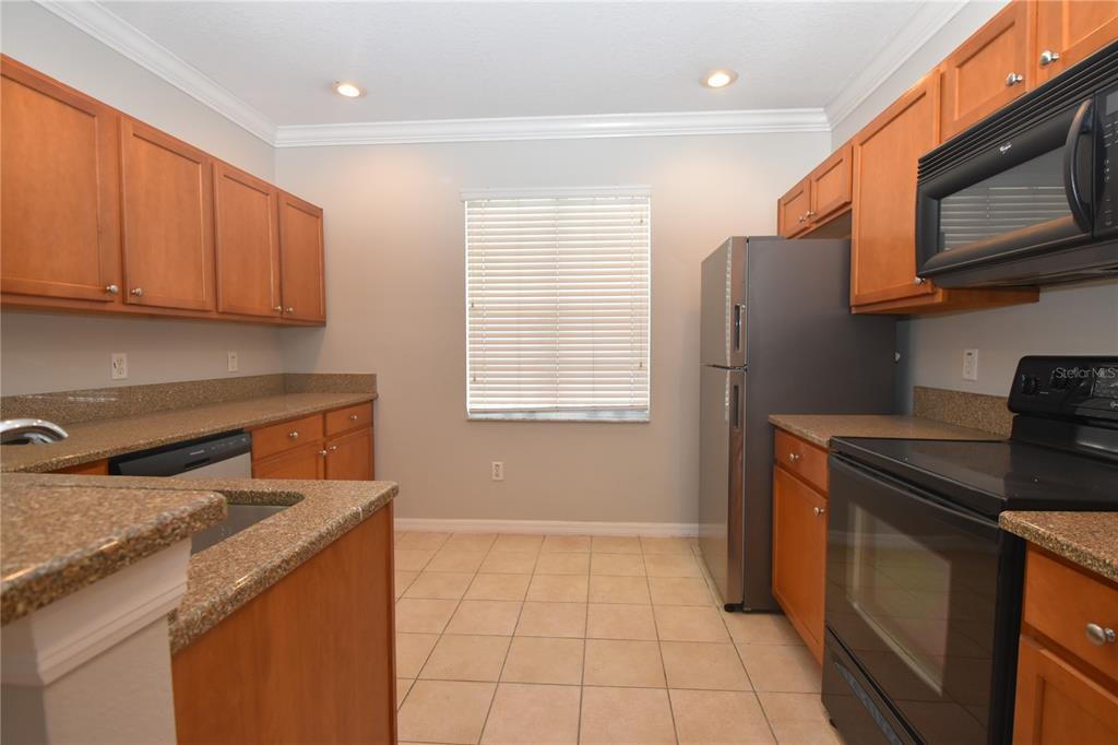A kitchen features wood cabinets, granite countertops, stainless steel appliances, and tile flooring — 4901 ELIZABETH ANNE CIRCLE, TAMPA, FL