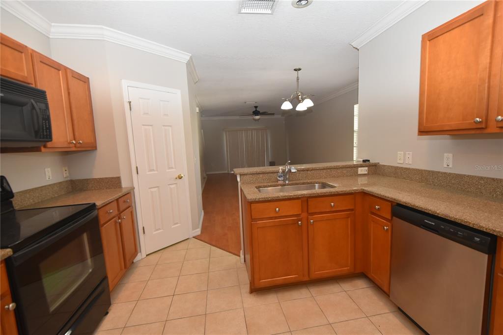 A kitchen with wood cabinets, granite countertops, tile flooring, and a stainless steel dishwasher — 4901 ELIZABETH ANNE CIRCLE, TAMPA, FL