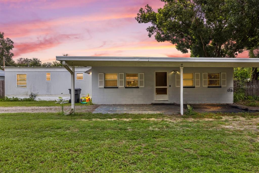 A single-story house with a gray block facade and a covered front porch at sunset — 1733 OAKLAND ROAD W, LAKELAND, FL