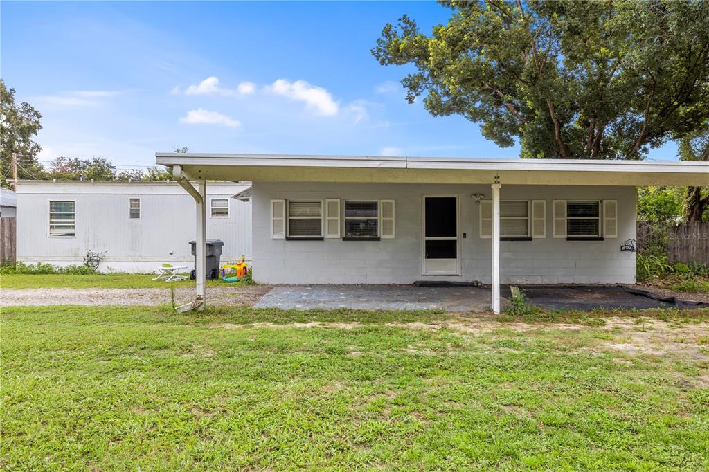 A single-story gray concrete block house with a front carport and a white mobile home — 1733 OAKLAND ROAD W, LAKELAND, FL