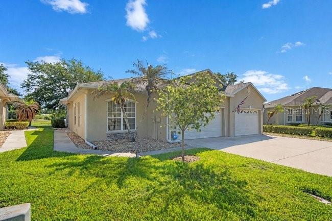 A tan single-story duplex with a two-car garage and a small front yard — 208 LAMONTE POINT CT, DEBARY, FL