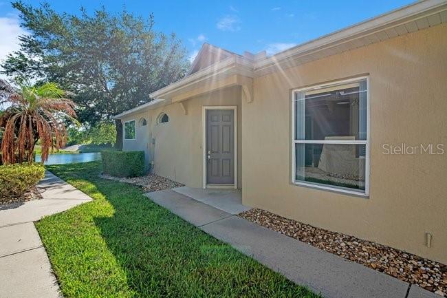 The exterior of a tan house features a front door, a window, and a walkway — 208 LAMONTE POINT CT, DEBARY, FL