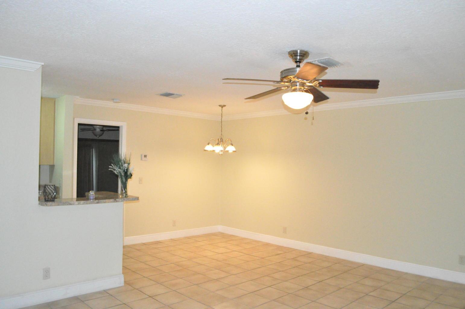 An open dining area features beige walls, tile flooring, a ceiling fan, and a chandelier — 10 Crossings Circle # A, Boynton Beach FL 33435, BOYNTON BEACH, FL