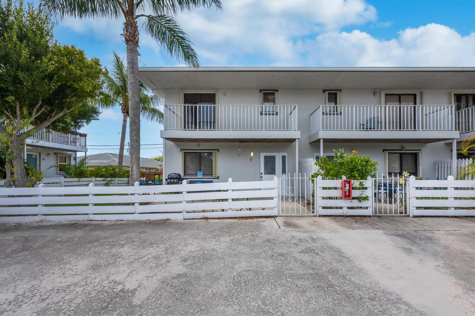 A two-story residential building features white balconies, a white picket fence, and a concrete driveway — 324 W Pine Street # 11, Lantana FL 33462, LANTANA, FL
