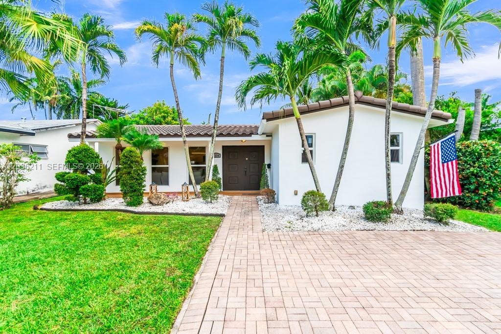 A white single-story house features a paved walkway, palm trees, and an American flag — 1234 Buchanan St, Hollywood FL 33019, HOLLYWOOD, FL