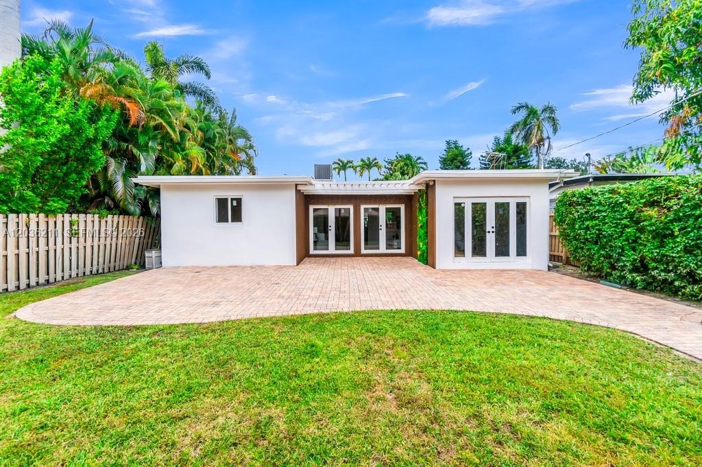 The exterior of a white house features a paved patio and a grassy backyard — 1234 Buchanan St, Hollywood FL 33019, HOLLYWOOD, FL