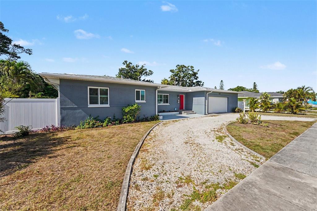 A gray single-story house with a red front door and a gravel driveway — 4660 22ND AVENUE S, ST PETERSBURG, FL