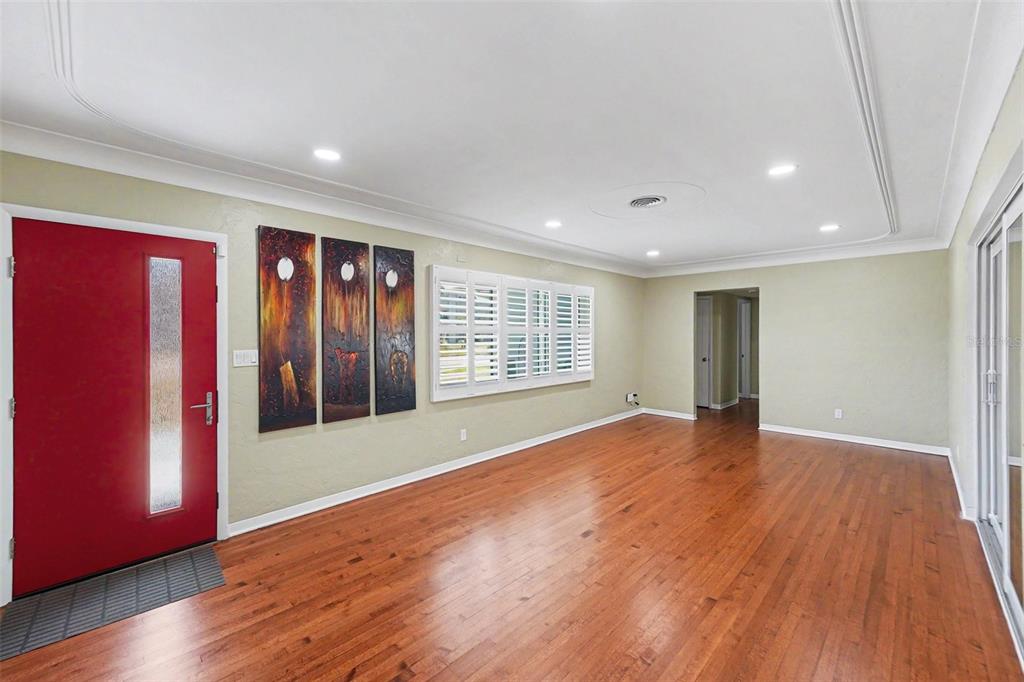 A living room with hardwood floors, a red front door, and white plantation shutters — 4660 22ND AVENUE S, ST PETERSBURG, FL