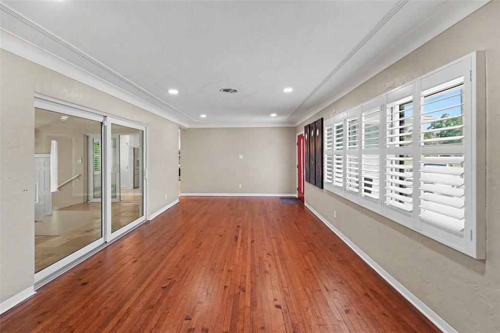 An empty room with hardwood floors, recessed lighting, plantation shutters, and sliding glass doors — 4660 22ND AVENUE S, ST PETERSBURG, FL