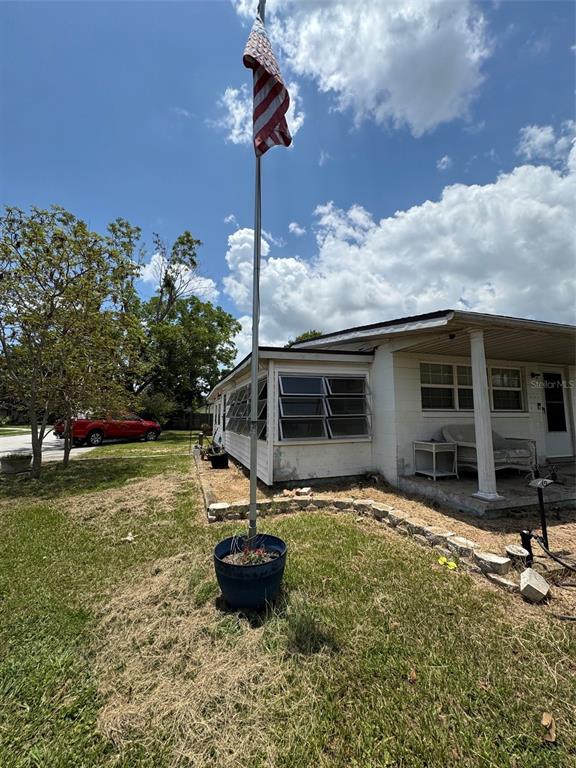 A flagpole stands in a blue planter in the yard of a white house — 1404 EMMETT STREET, KISSIMMEE, FL