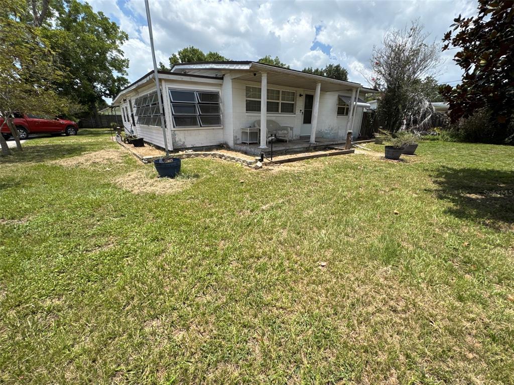 A white single-story house with a covered front porch sits on a grassy lot — 1404 EMMETT STREET, KISSIMMEE, FL