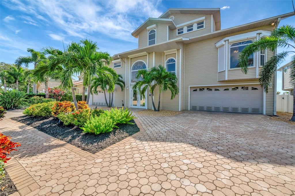 A two-story beige house with a paved driveway, palm trees, and a multi-car garage — 5918 SKIMMER POINT BOULEVARD S, GULFPORT, FL