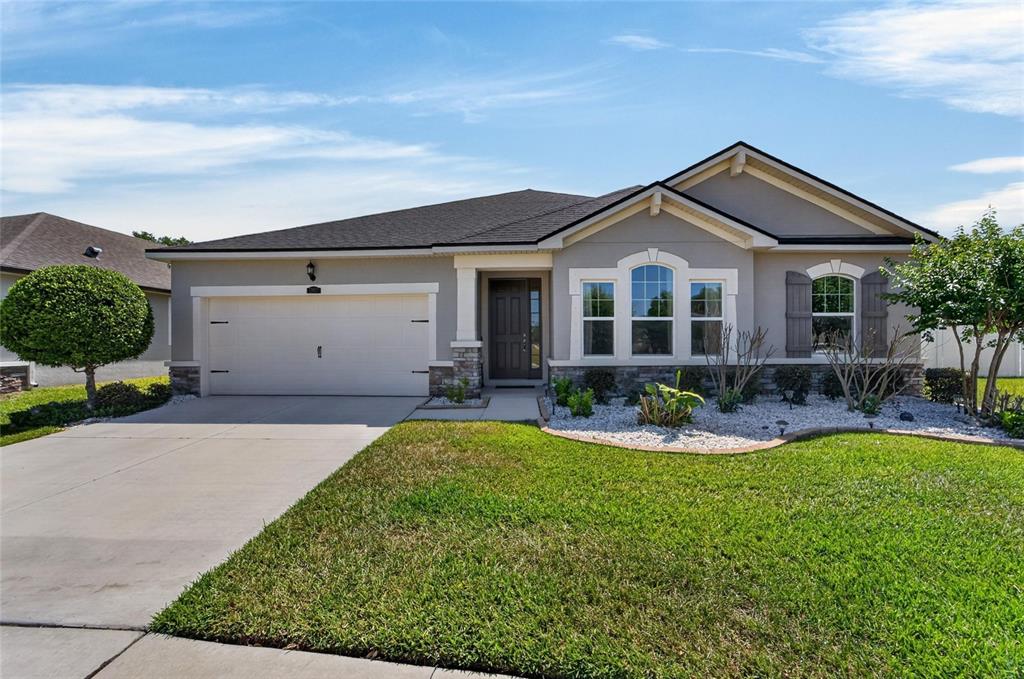 A single-story house with a two-car garage, stone accents, and a landscaped front yard — 13017 SATIN LILY DRIVE, RIVERVIEW, FL