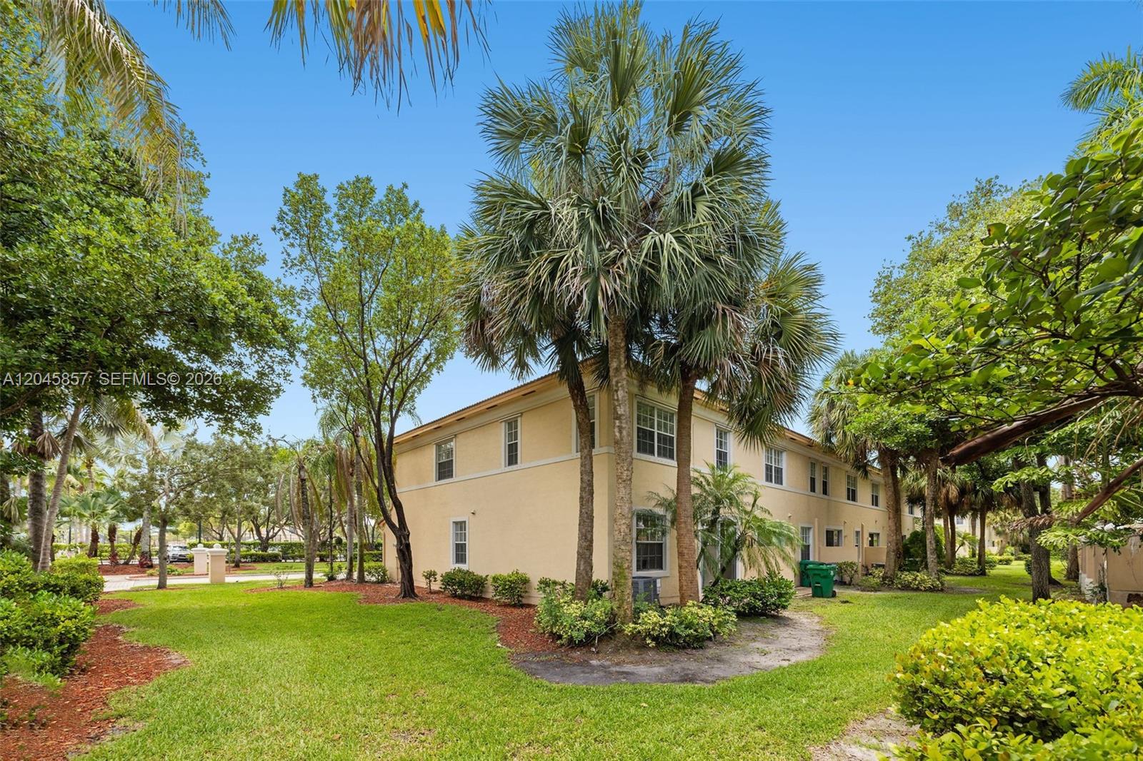 A two-story tan apartment building is surrounded by lush green trees and landscaping — 8401 SW 25th Ct # 106, Miramar FL 33025, MIRAMAR, FL