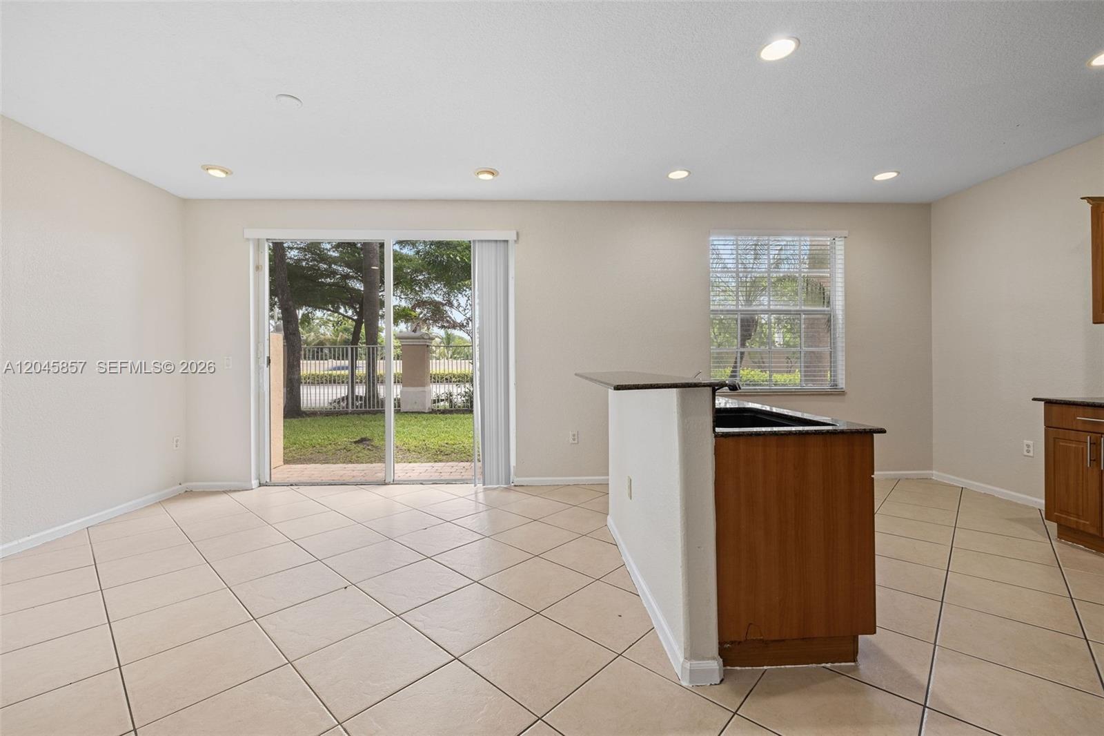 A kitchen with a breakfast bar and tile flooring overlooks a backyard through sliding doors — 8401 SW 25th Ct # 106, Miramar FL 33025, MIRAMAR, FL