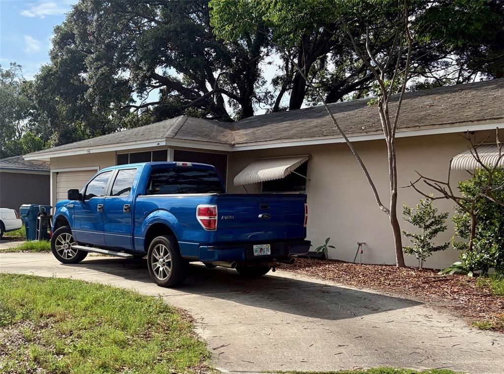A single-story house with a beige exterior, a screened porch, and a concrete driveway — 7179 SPRING HILL DRIVE, SPRING HILL, FL