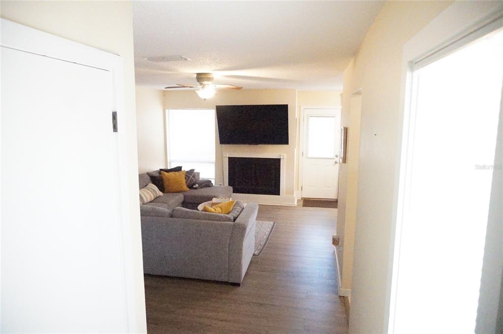 A living room features a grey sectional sofa, a fireplace with a mounted television, and wood-look flooring — 695 & 693 BELFLOWER PLACE, ALTAMONTE SPRINGS, FL