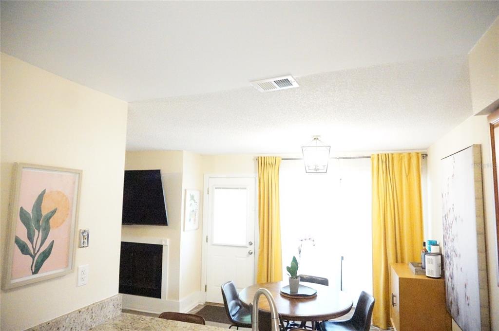 A dining area features a round wooden table, yellow curtains, and a fireplace — 695 & 693 BELFLOWER PLACE, ALTAMONTE SPRINGS, FL