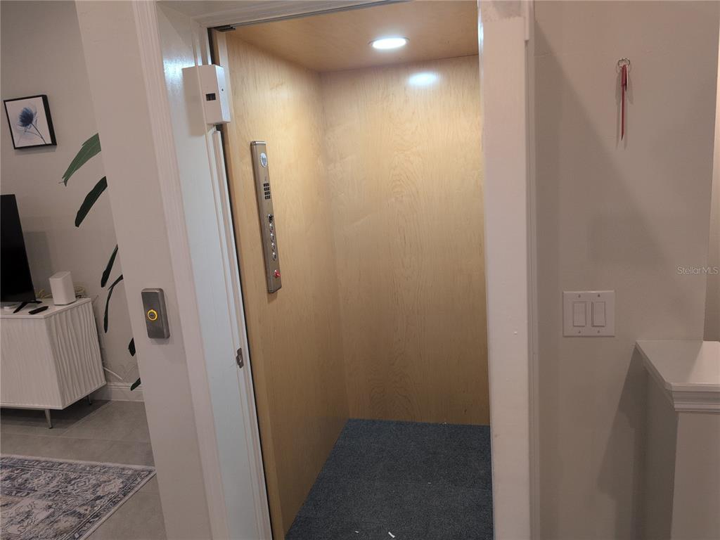 A residential elevator with light wood paneling and a gray carpeted floor — 10420 CORAL LANDINGS LANE UNIT 115, PLACIDA, FL