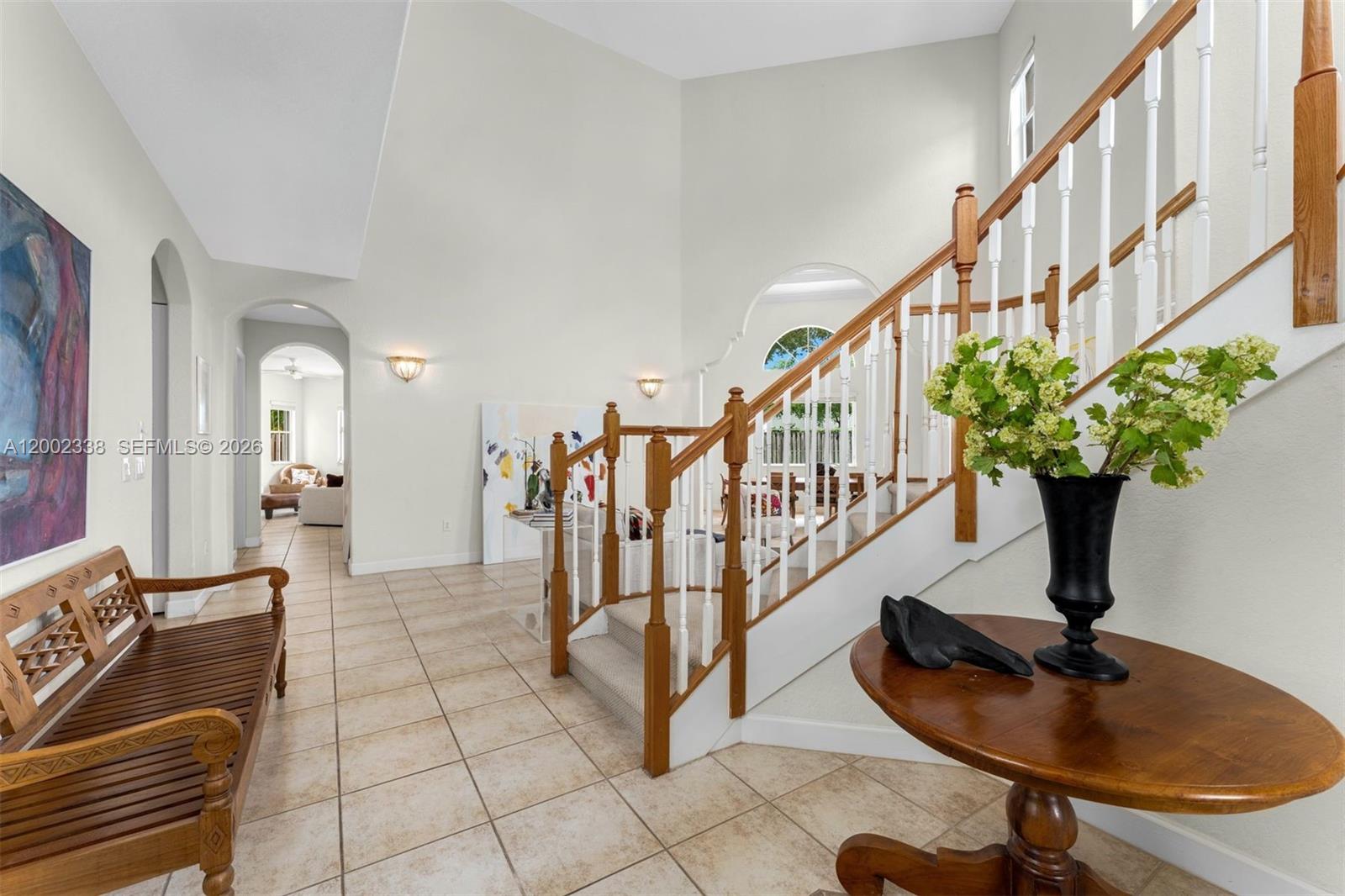 A foyer features a wooden bench, a round table with a vase, and a staircase — 6914 NW 113th Pl, Doral FL 33178, DORAL, FL