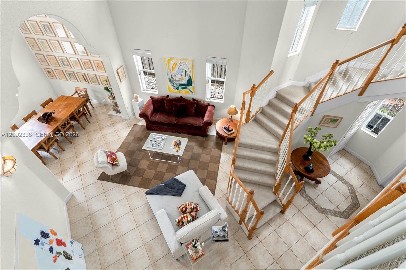 An elevated view of a living and dining area with a curved staircase and tile floors — 6914 NW 113th Pl, Doral FL 33178, DORAL, FL