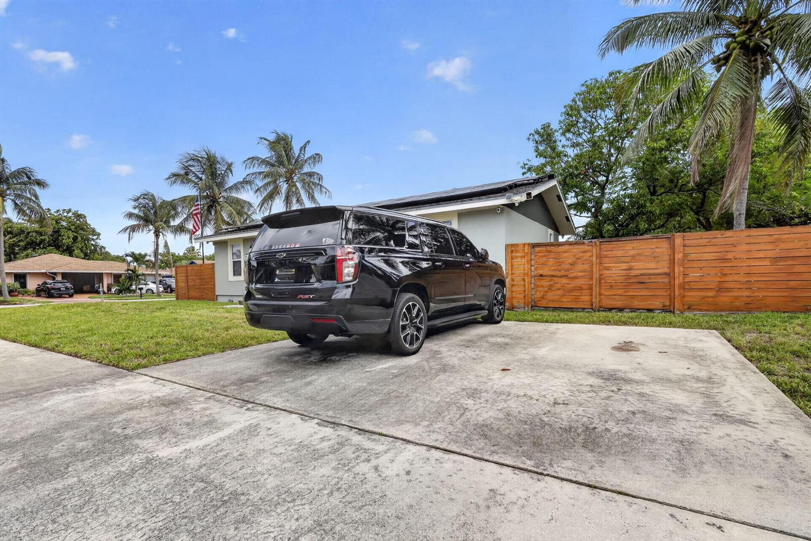A black SUV is parked on a concrete driveway in front of a house — 202 Elaine Circle W, West Palm Beach FL 33409, WEST PALM BEACH, FL