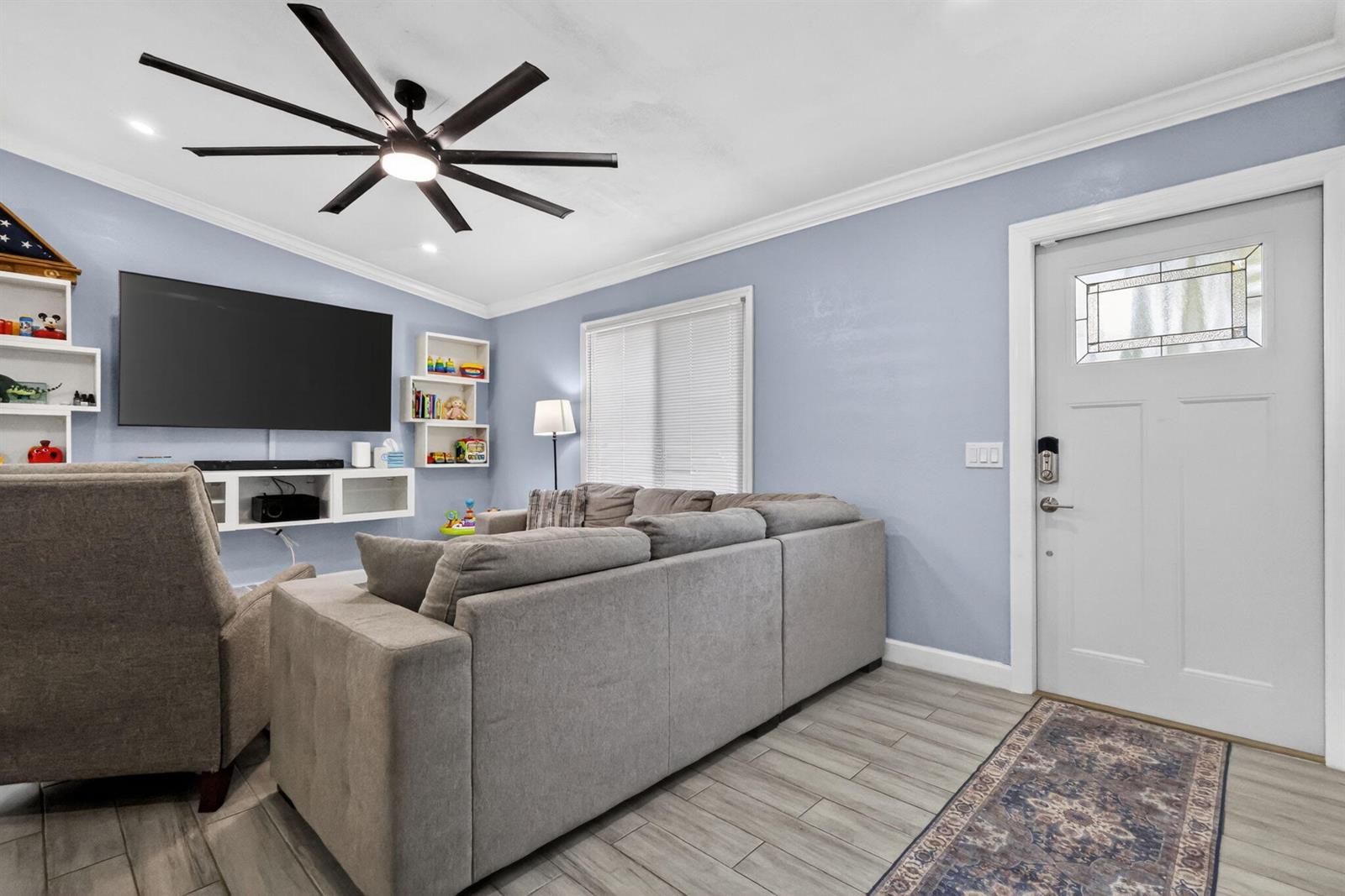 A living room features light blue walls, a gray sectional sofa, and a ceiling fan — 202 Elaine Circle W, West Palm Beach FL 33409, WEST PALM BEACH, FL